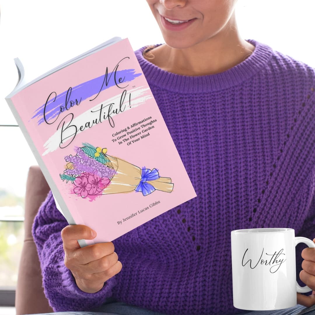 A woman in a purple sweater holding the Color Me Beautiful coloring book